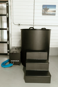 Round black ice bath tub with the lid on, insulated chiller and three-step entry platform